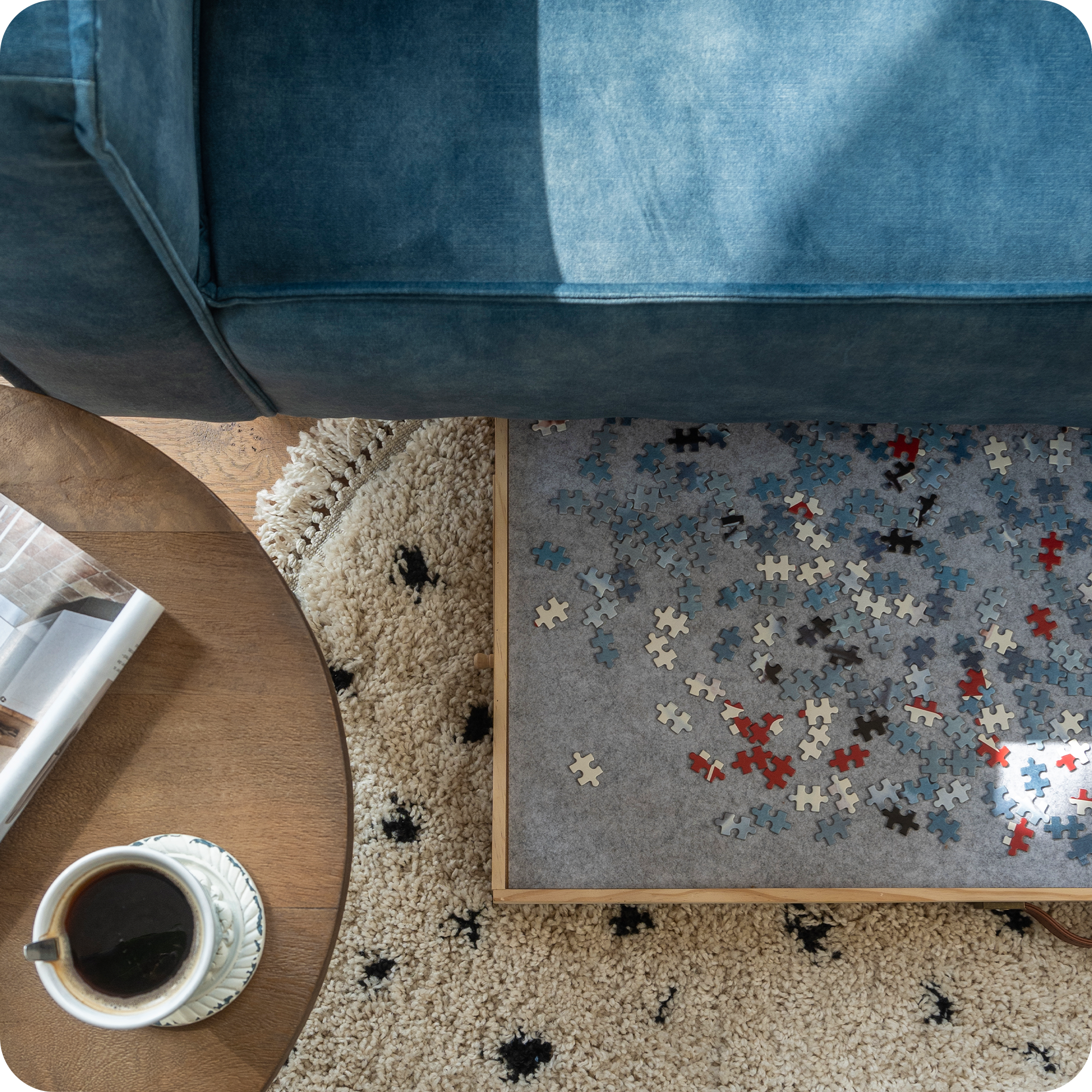 Bovenaanzicht van de landelijke woonkamer met de blauwe bank. Onder de blauwe bank ligt de verstelbare puzzelplaat met puzzelstukjes erop. Deze wordt opgeborgen onder de bank.